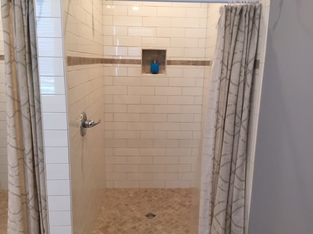A tiled walk-in shower with a curtain.
