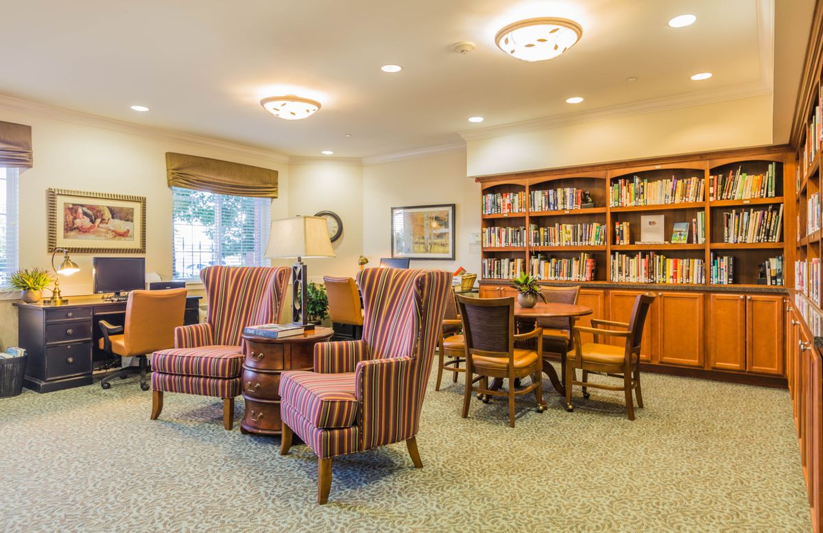 A cozy library reading room with comfortable chairs and bookshelves filled with books.