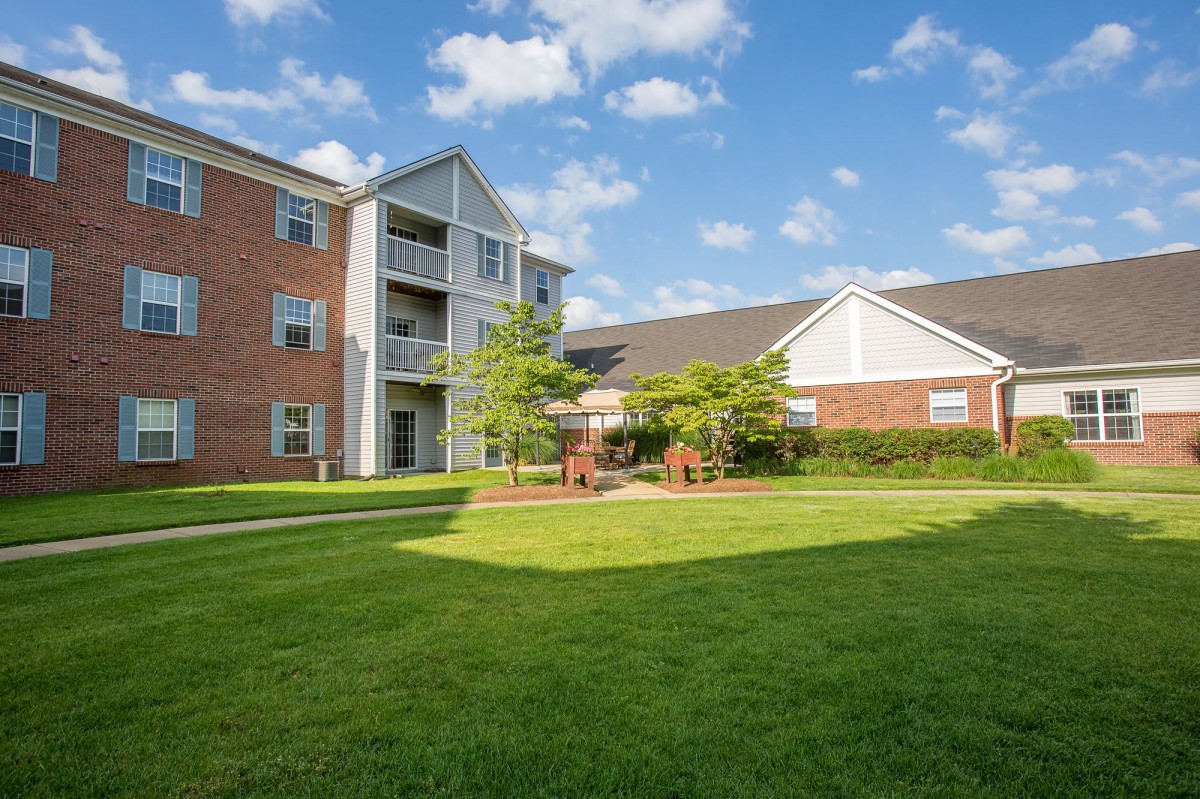 A modern apartment building with a well-maintained lawn and landscaping on a sunny day.
