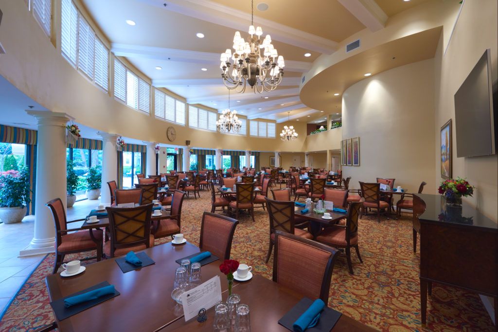 An elegant and spacious dining area with chandeliers, neatly arranged tables, and comfortable seating.