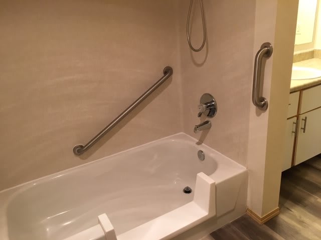 A bathroom with a bathtub equipped with grab bars for safety.