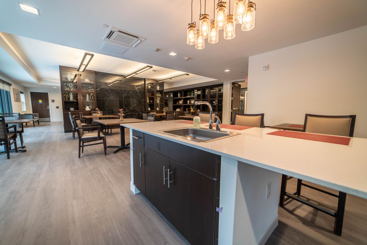 A modern kitchen with an island and dining area featuring elegant lighting.