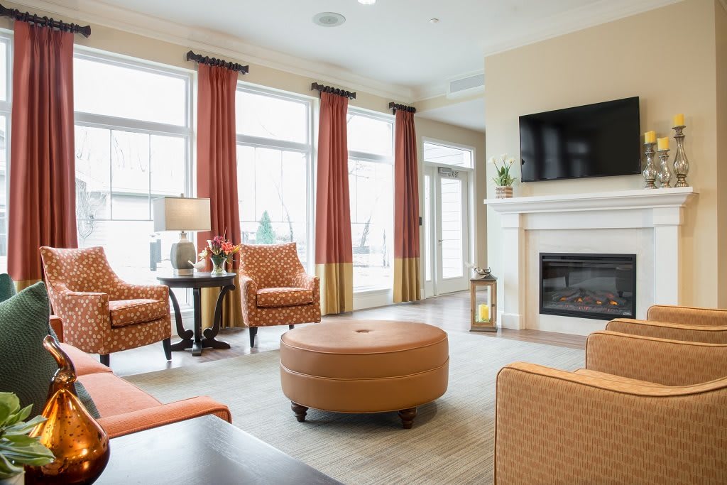 A modern living room featuring a cozy seating area with a fireplace and large windows.
