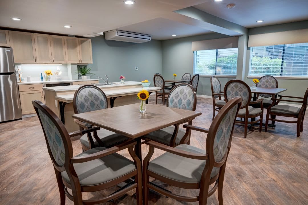 A modern dining room with a table, chairs, and an adjacent kitchen area.