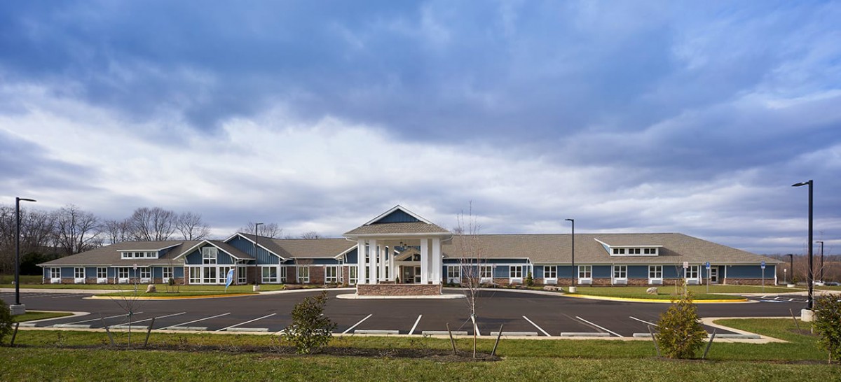 A modern building with a spacious parking lot under a cloudy sky.