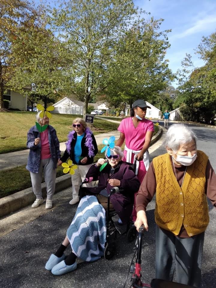 A group of elderly people enjoying a walk outdoors in the neighborhood on a sunny autumn day.