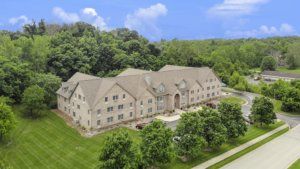 Aerial view of a large stone building surrounded by lush greenery and trees.