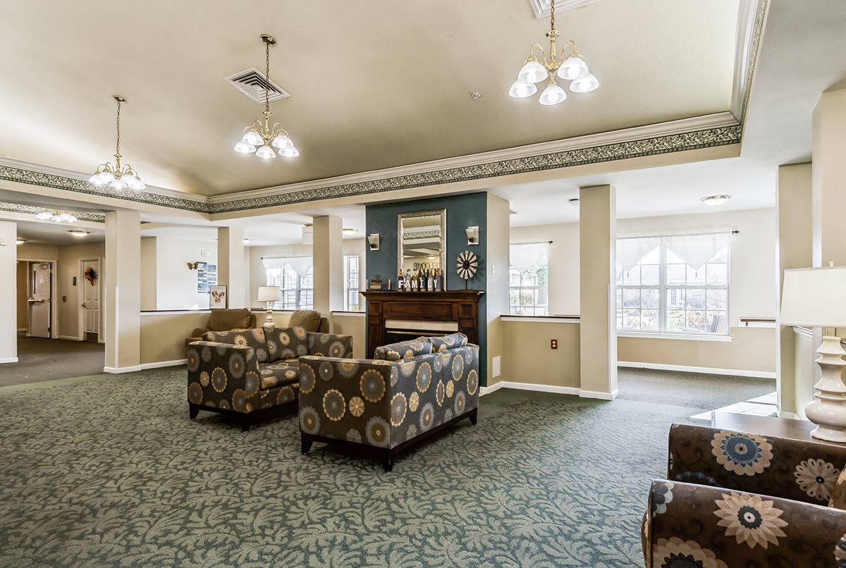 A spacious living room with patterned sofas and a fireplace, illuminated by chandeliers.