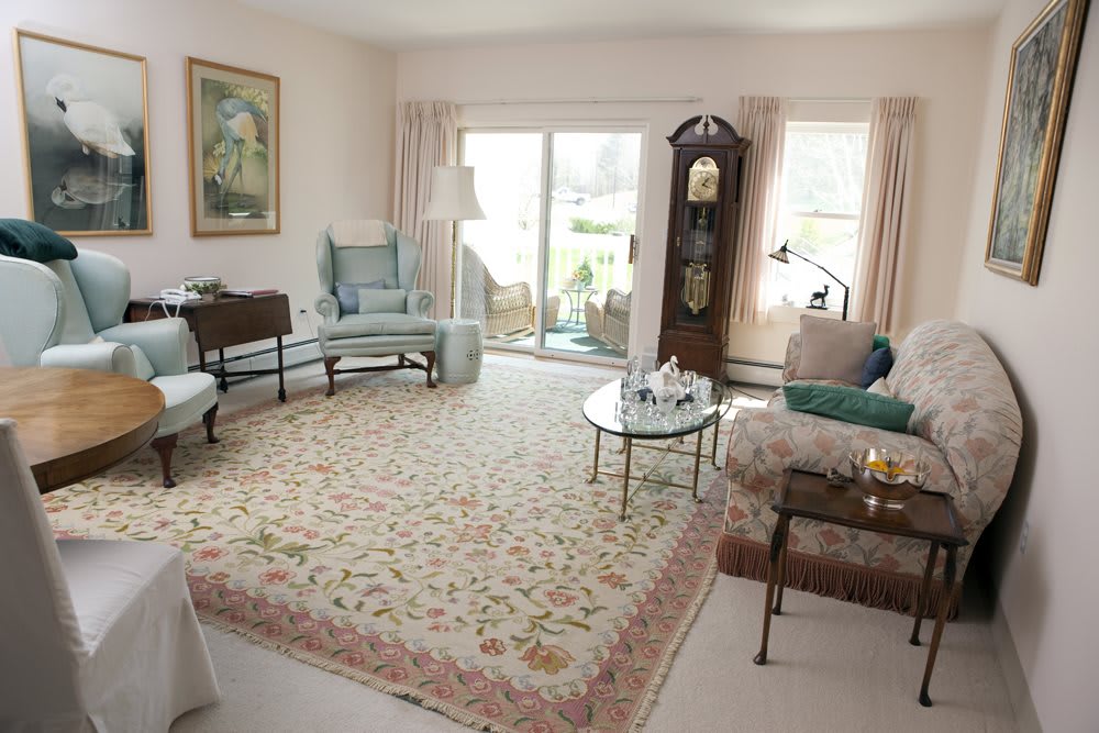 A traditional living room with elegant furniture, including a grandfather clock and a large floral rug.