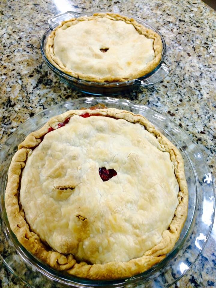 Two freshly baked pies with decorative crusts on a granite countertop.