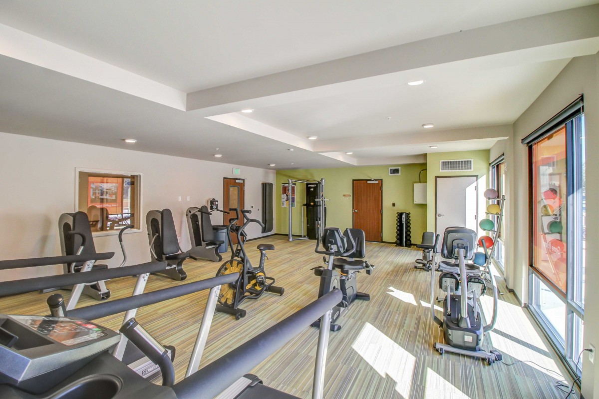 A well-equipped gym with various exercise machines and weights, brightly lit and inviting for workouts.