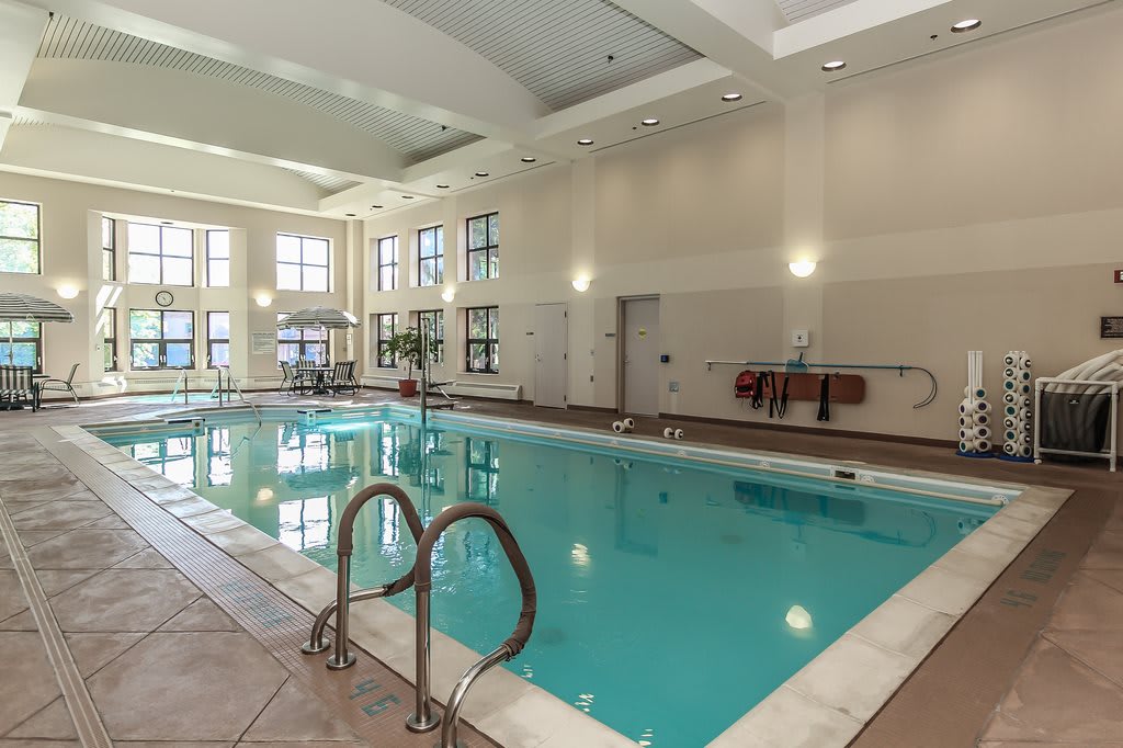 An indoor swimming pool with large windows and ample lighting.