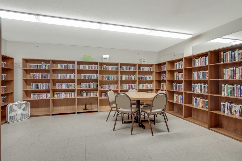 A quiet library corner with bookshelves and a round table surrounded by chairs.