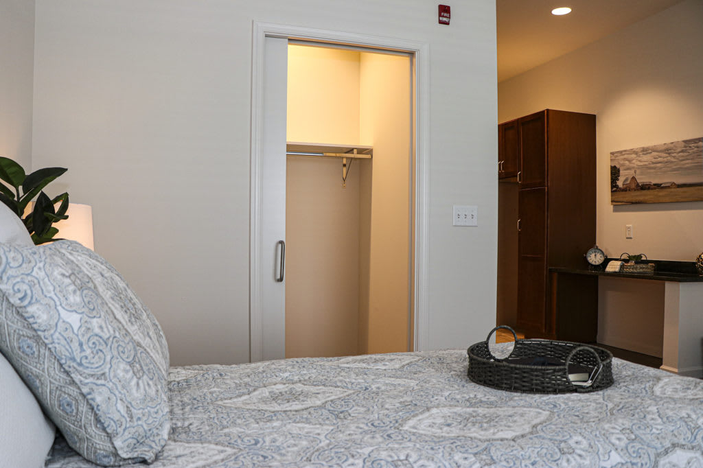 A cozy bedroom featuring a bed with patterned linens and an open closet door.