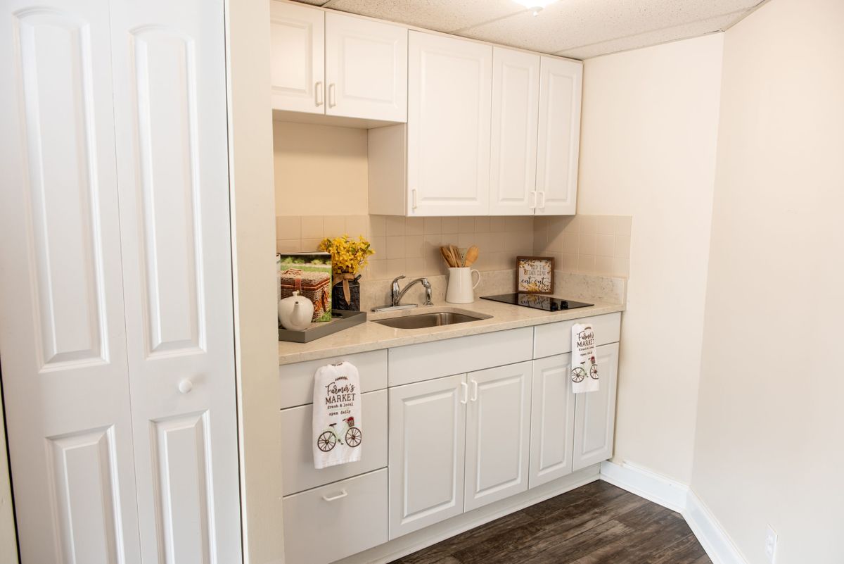 A cozy kitchen setup featuring white cabinets, a sink, and decorative items on the countertop.