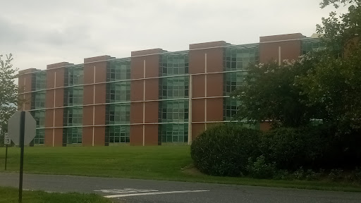A modern brick building with large windows surrounded by grass and shrubs.