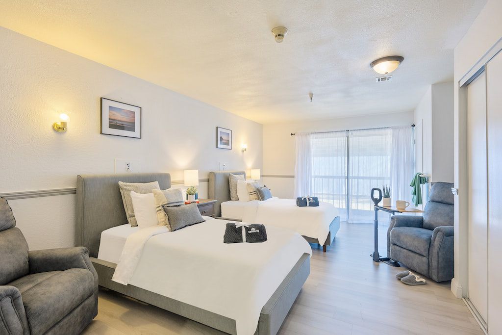 A modern hotel room with two neatly made beds, light decor, and comfortable furnishings.