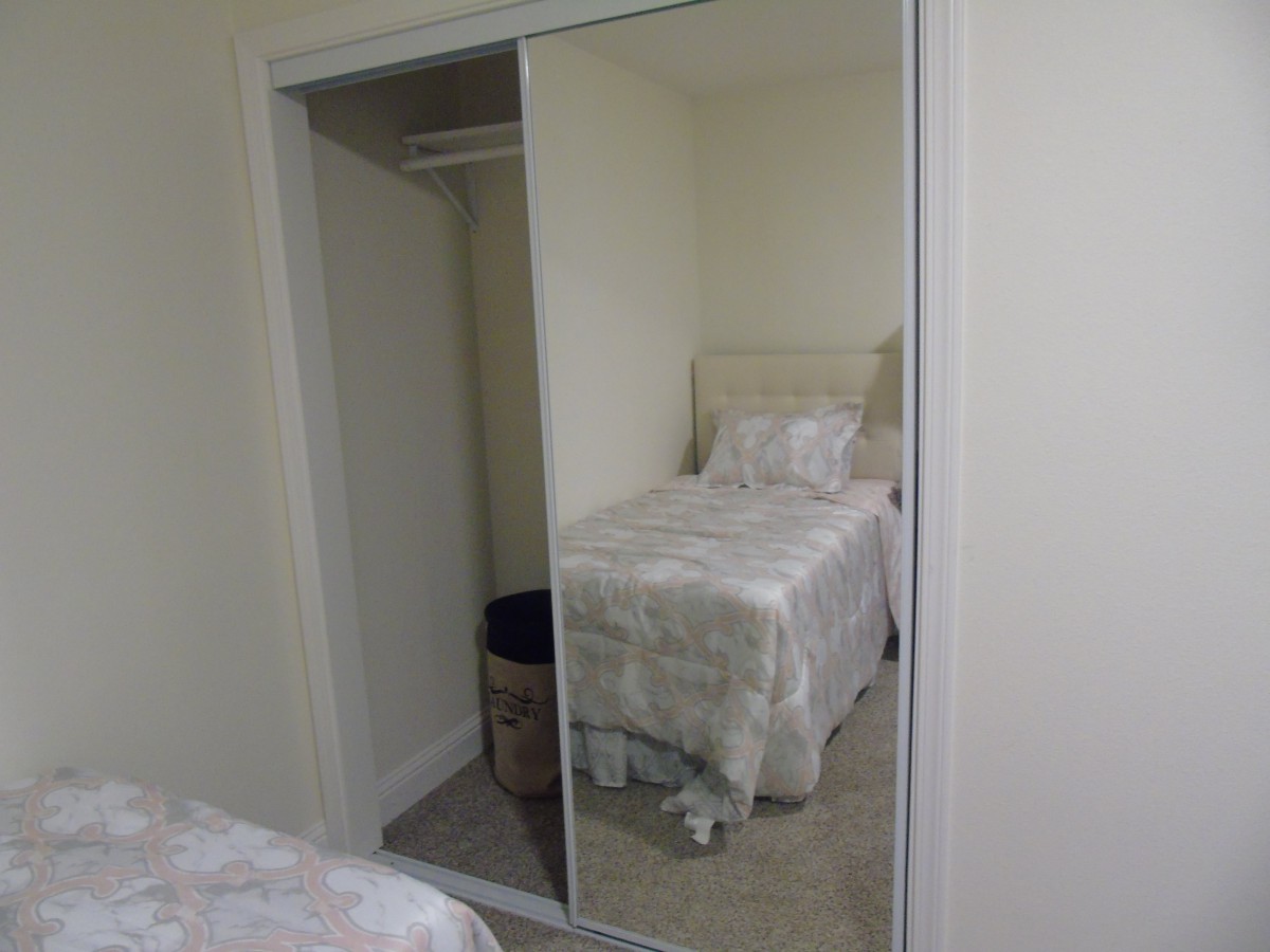 A minimalist bedroom with a single bed and mirrored closet doors.
