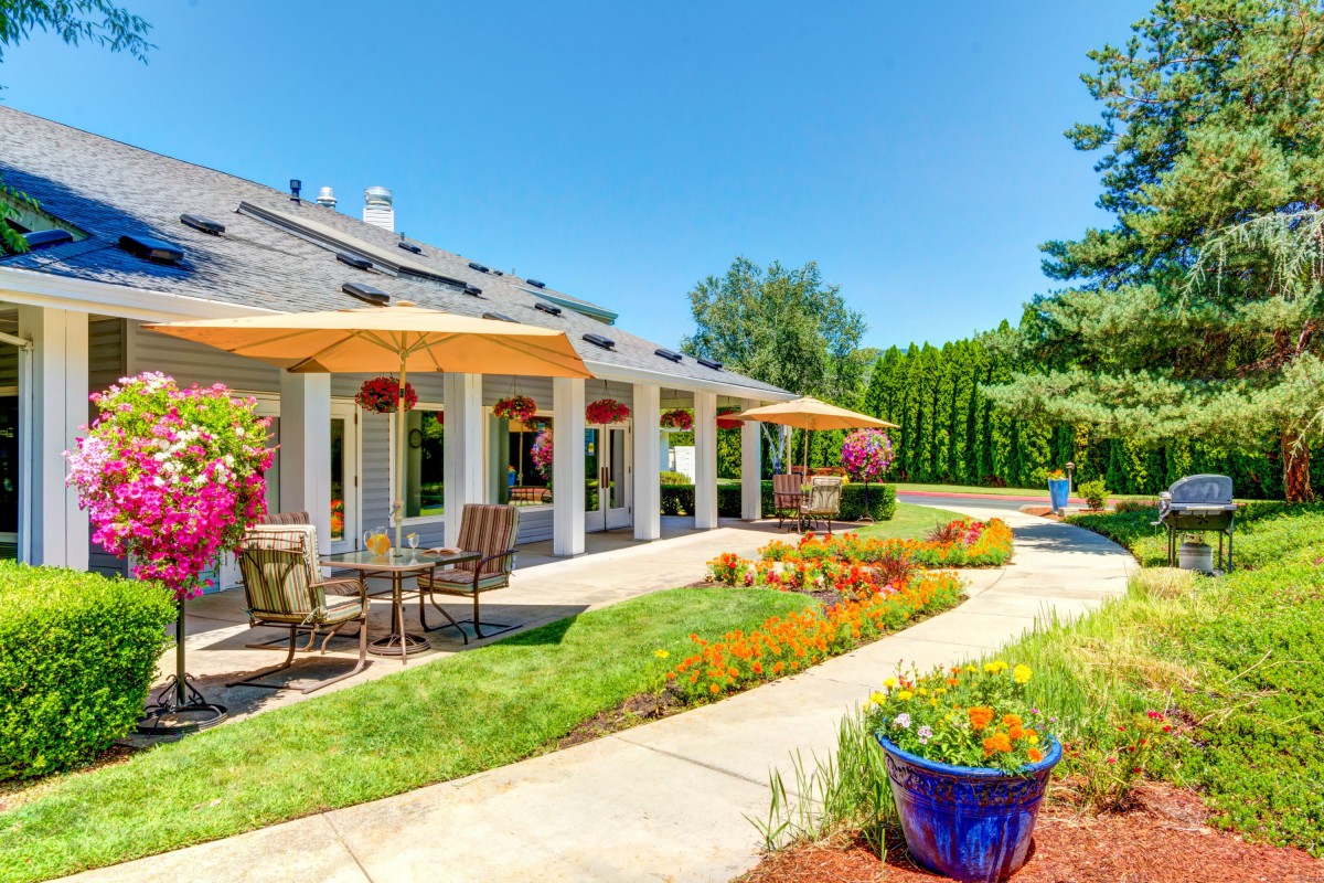 A beautiful patio area with outdoor seating and vibrant garden landscaping on a sunny day.