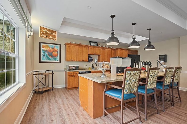 A modern kitchen with wooden cabinets, an island with bar stools, and pendant lighting.