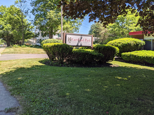 A beautifully landscaped area featuring a sign surrounded by lush greenery and a clear blue sky.