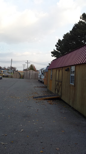 A quiet scene featuring a row of wooden sheds with a red roof in an outdoor setting.