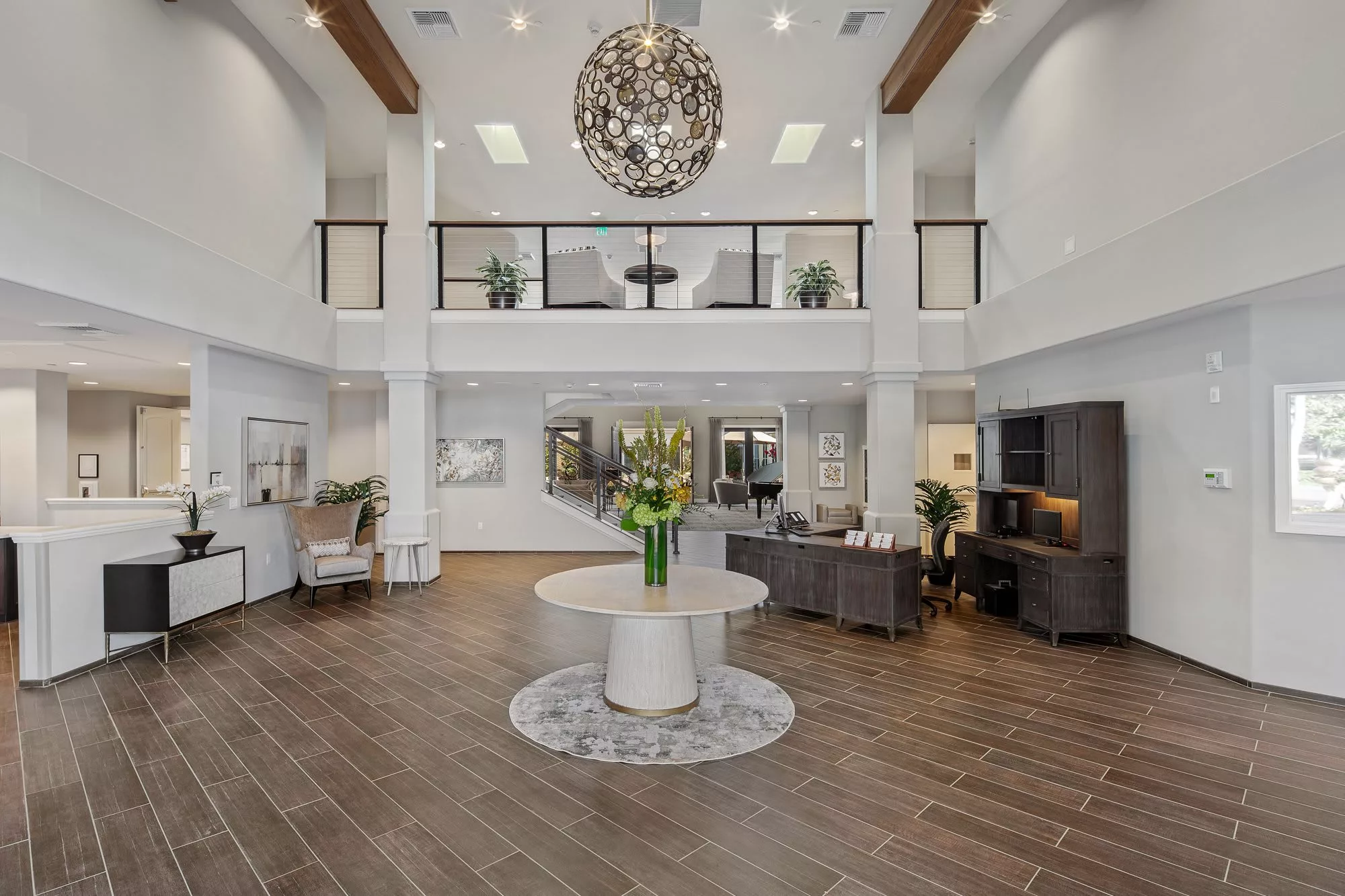 A modern lobby with high ceilings, featuring a large chandelier, elegant furniture, and stylish decor.