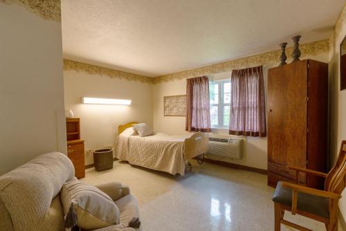 A cozy and simple bedroom featuring a single bed, a comfortable chair, and soft curtains.