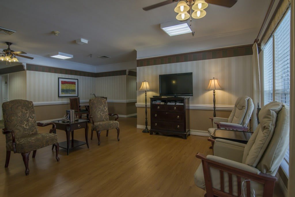 A cozy living room with comfortable chairs, a TV, and soft lighting.