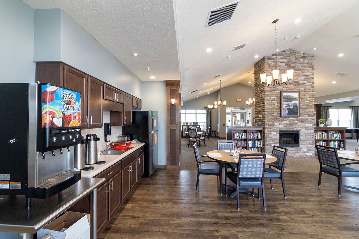 A modern community space featuring a kitchen and dining area with wood flooring and stylish lighting.