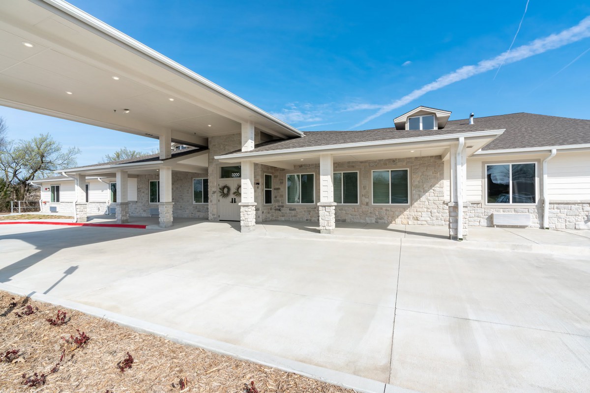 A modern building entrance with a covered driveway and columns.