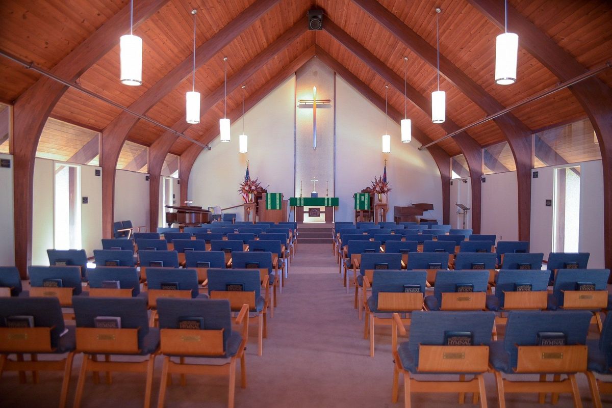 A view of a church interior with rows of pews leading up to the altar.