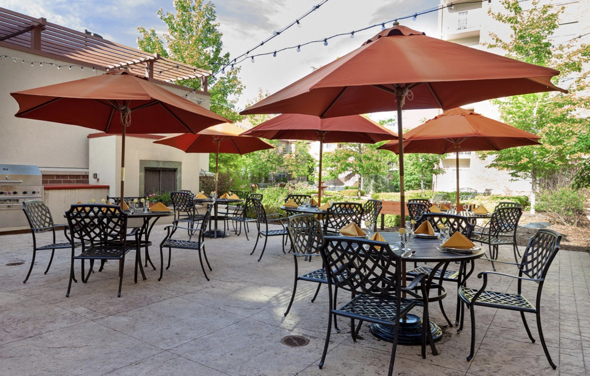 A sunny outdoor patio with tables and umbrellas, ready for dining.