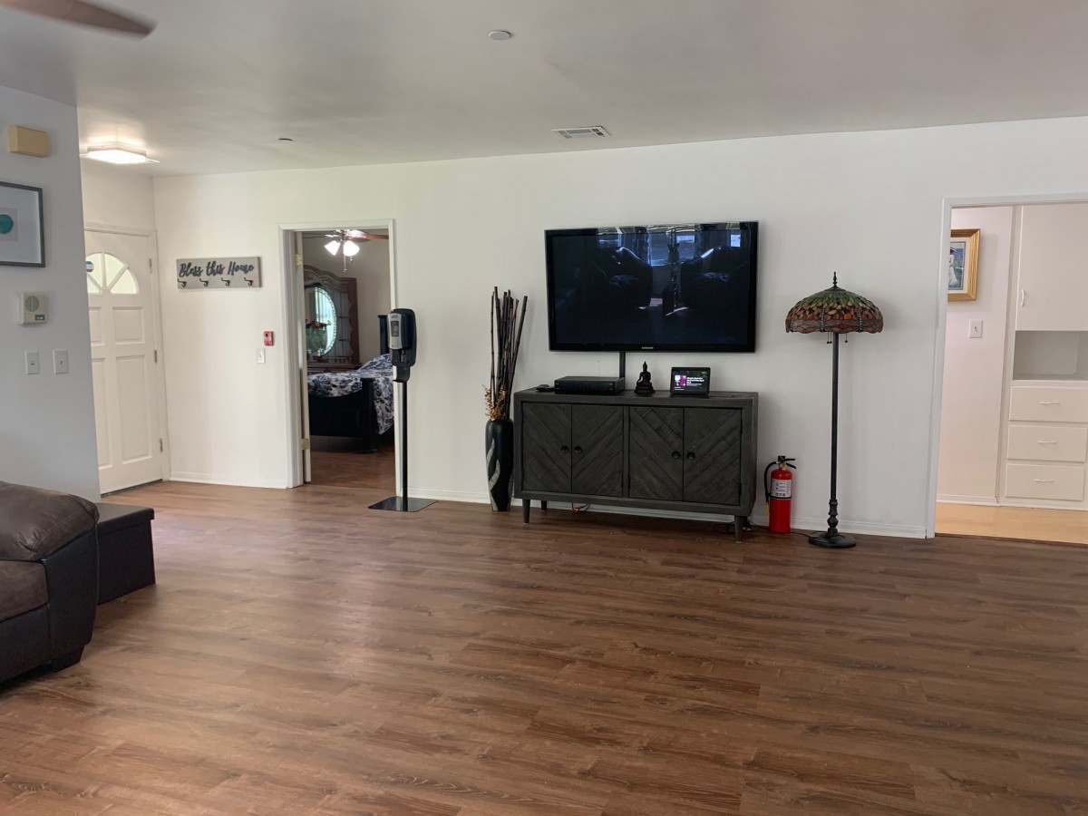 A spacious living room featuring a television mounted on the wall with minimalist decor and wooden flooring.