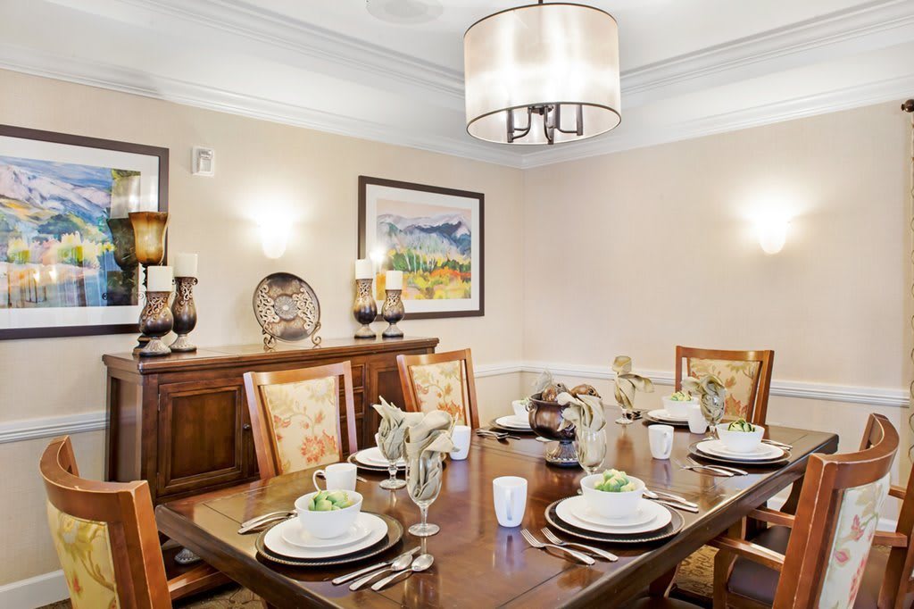 A beautifully set dining room with elegant tableware and a modern chandelier.