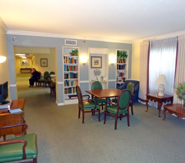 A cozy lounge area with chairs, tables, and bookshelves.