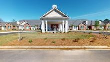 A wide entrance with columns leading to a residential building under a clear blue sky.