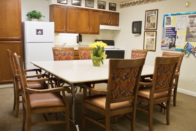A kitchen dining area with a large table, chairs, and cabinetry.