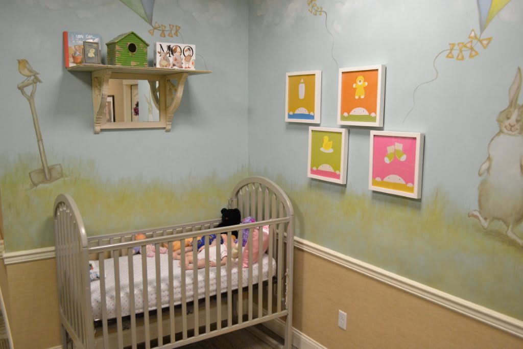 A cozy nursery featuring a crib and colorful wall art, perfect for a baby.