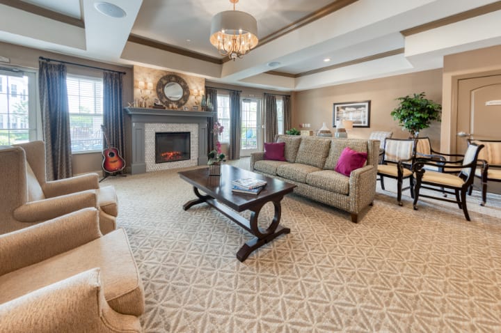 A spacious and elegantly designed living room featuring a comfortable sofa, a classic fireplace, a central wooden coffee table, and tasteful decor elements.