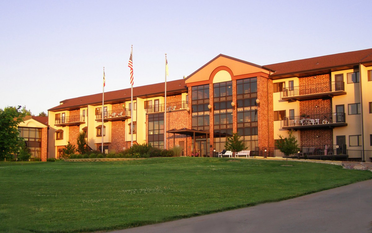 A hotel building with a well-maintained lawn and multiple flags displayed in front.