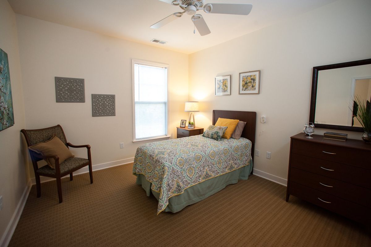 A cozy bedroom with a single bed, bedside lamp, and simple decor.