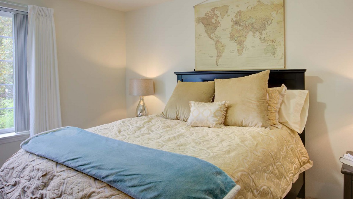 A cozy bedroom with a world map decoration above the bed and soft lighting.
