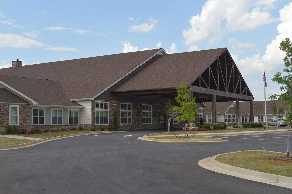 A large building with a peaked roof and surrounding driveway under a partly cloudy sky.