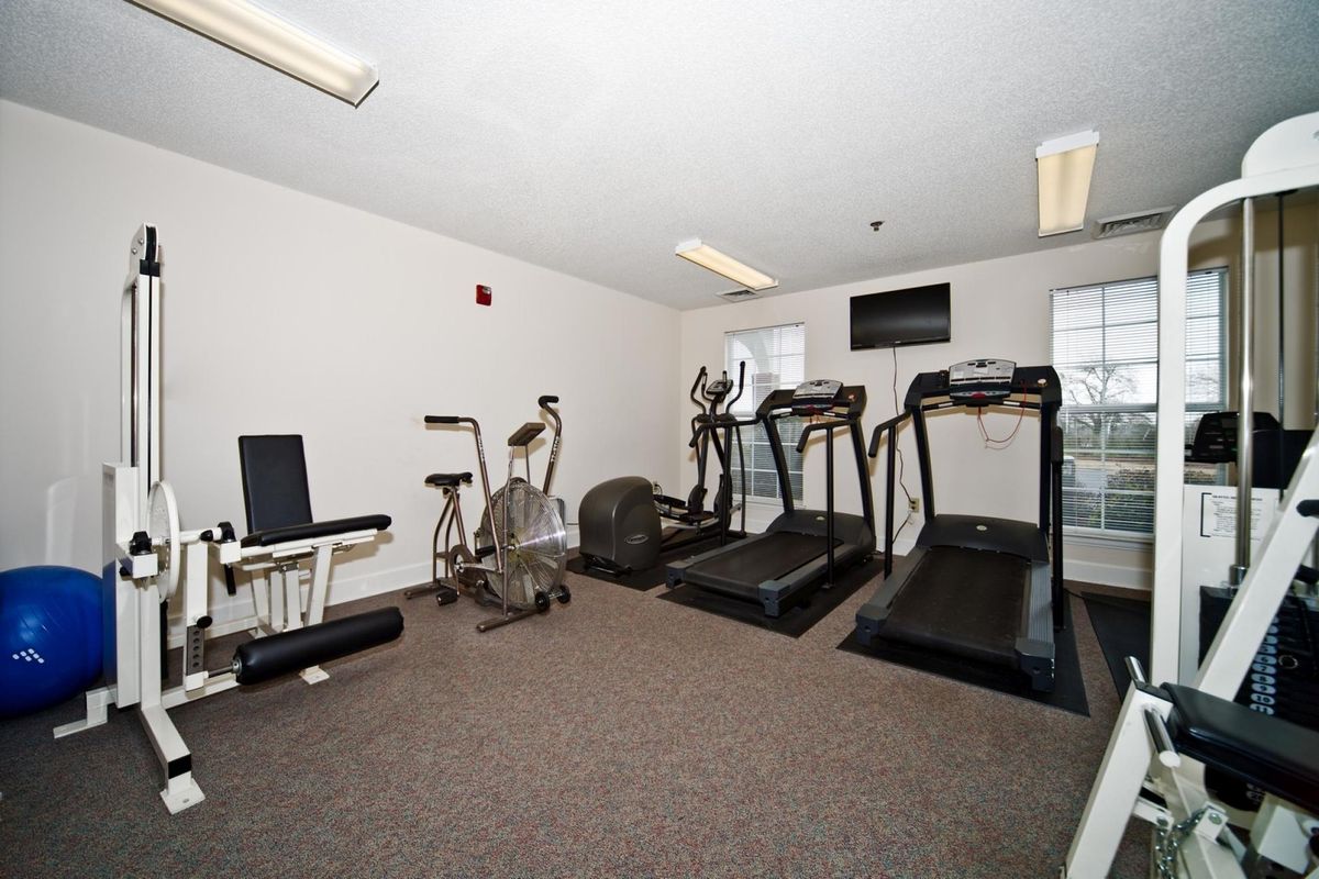 A small indoor gym with treadmills, exercise bikes, and various fitness equipment.