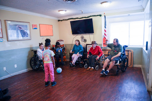 A young child engages with a group of seniors in wheelchairs during an interactive activity at a community center.