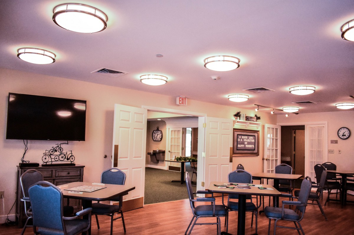 A cozy dining area with tables and chairs arranged under ceiling lights.