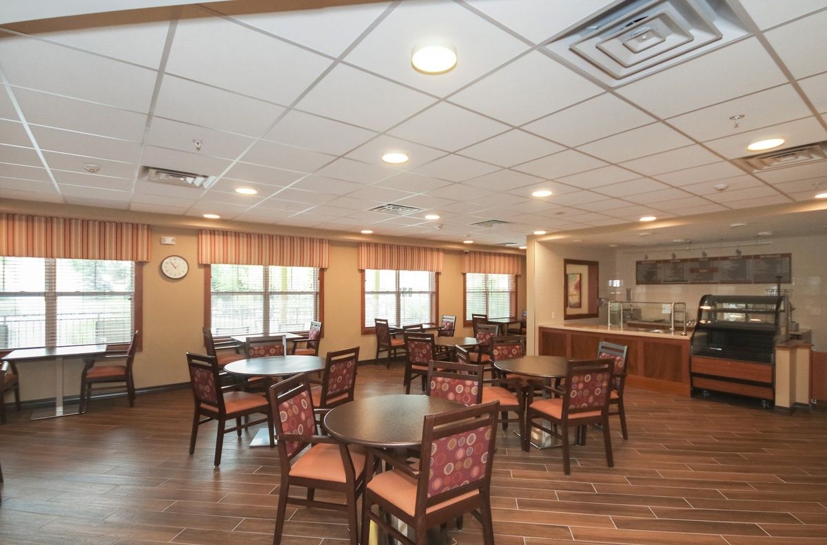 A cozy dining area with round tables, chairs, and warm lighting.