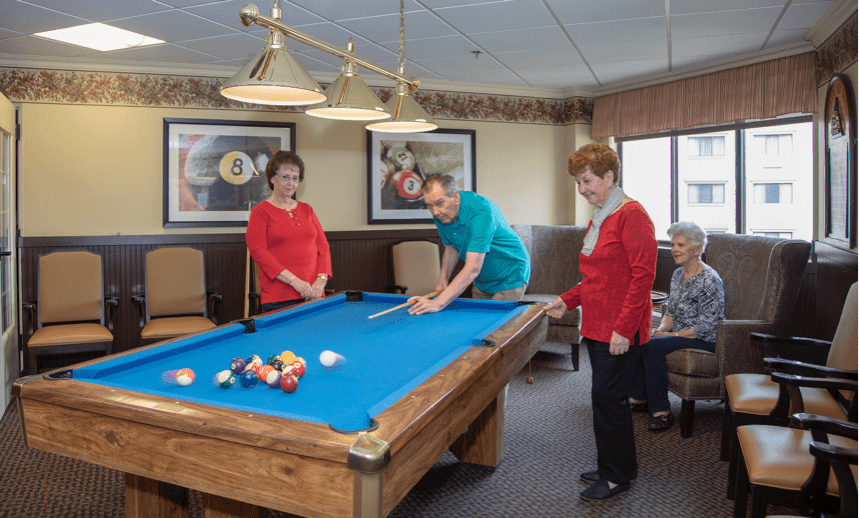 A group of seniors enjoying a game of billiards in a recreation room.