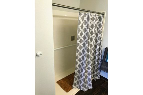 A bathroom with a patterned shower curtain partially open.